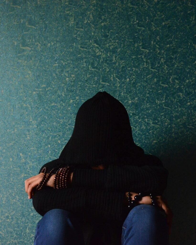 A person sits alone in a hoodie, conveying a sense of solitude and introspection.