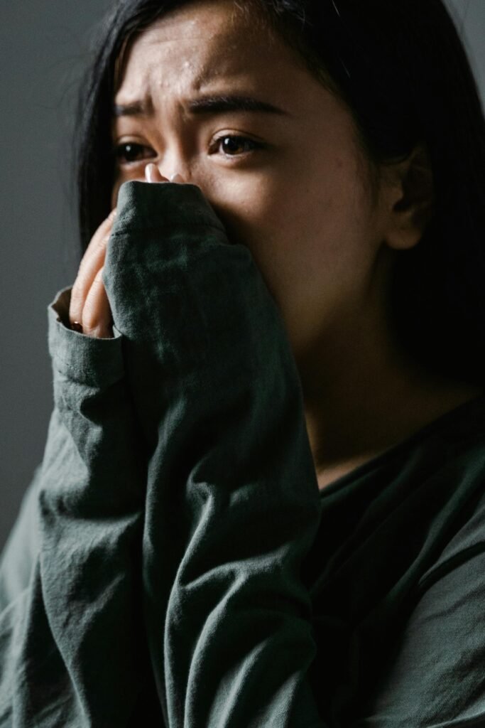 Close-up of a distressed woman indoors, showing anxiety and stress.